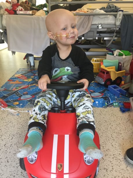Bryon riding his red car in hospital